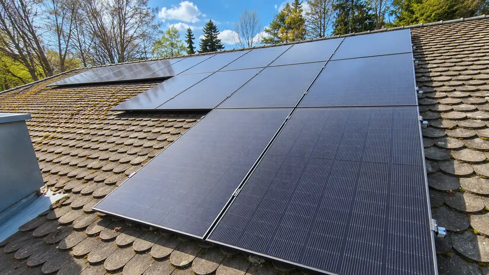 Montierte Full-Black PV-Module auf einem Dach in Bayerbach mit Hybrid-Wechselrichter, Heimspeicher und Hems im Keller und einer Wallbox in der Garage.