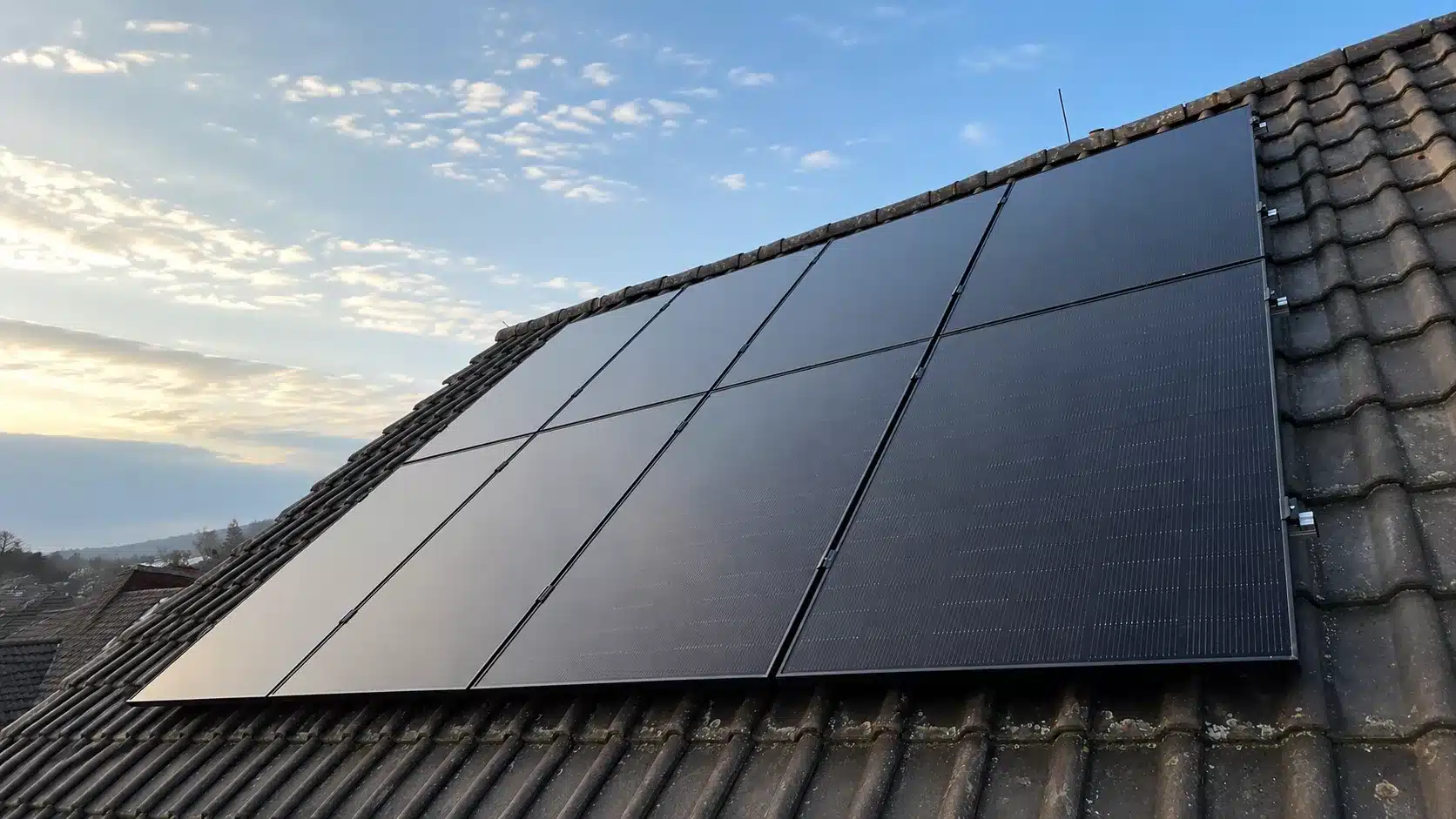 Montierte Full-Black PV-Module auf einem Dach in Cham mit Hybrid-Wechselrichter, Heimspeicher, Ersatzstrombox und Hems im Keller.